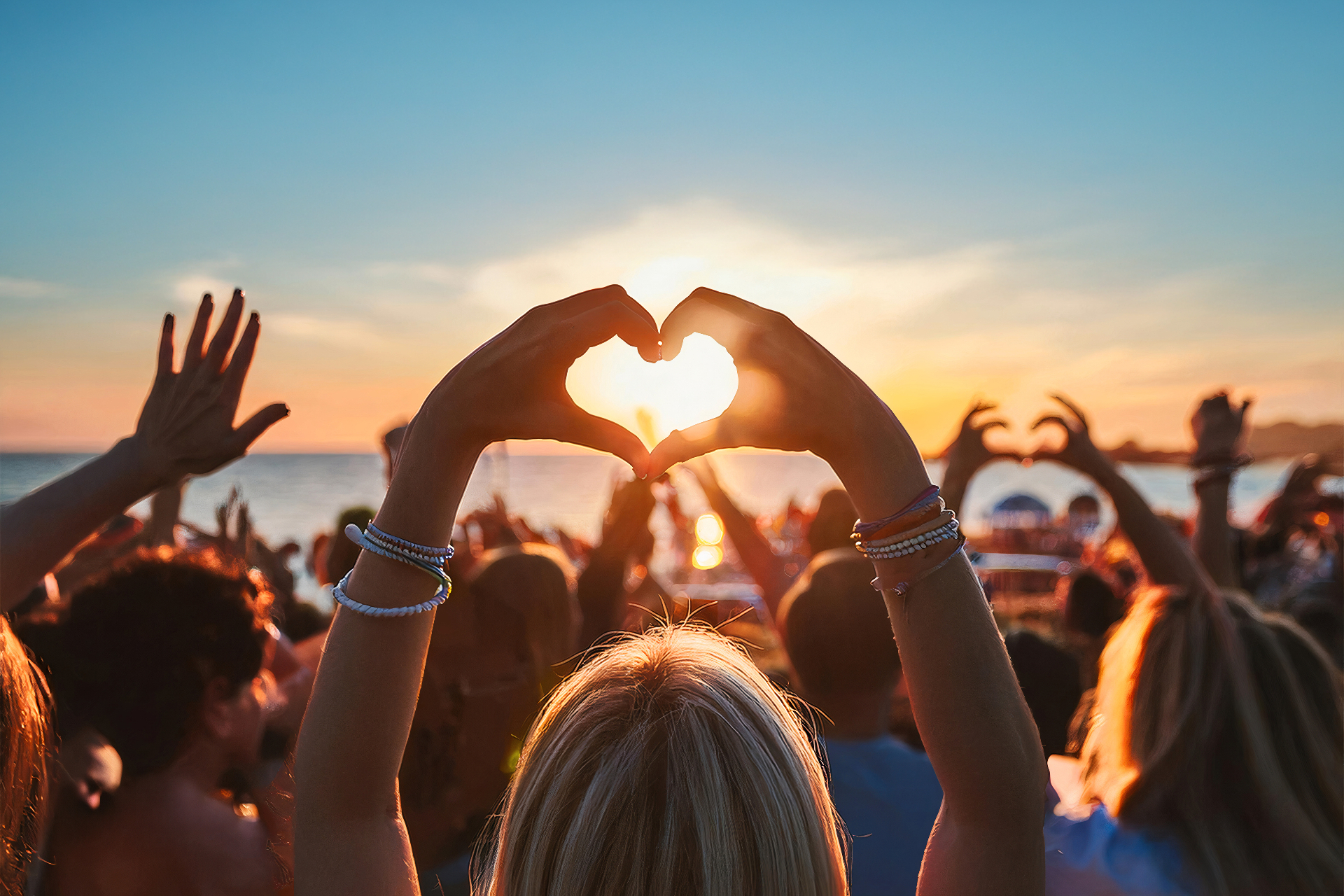 Sirenen-Crowd mit Herzhänden im Sonnenuntergang am Meer